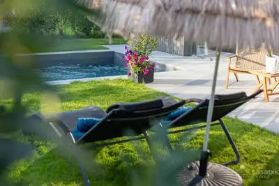 a lawn chair sitting in the grass next to a pool at Gite SIWA pour 2 personnes in Verviers