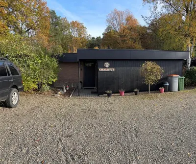 a black building with a car parked in front of it at Vakantiehuis chaletje in Lanaken