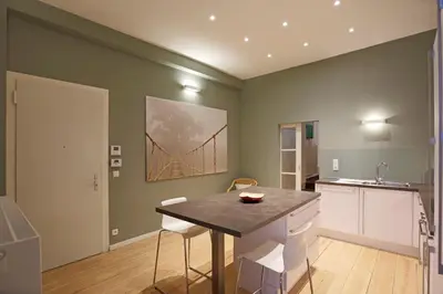 a kitchen with a table and a bridge painting on the wall at Aparthotel Liège in Liège