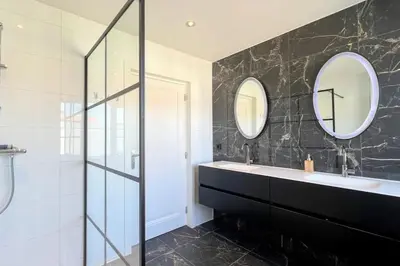 a bathroom with a sink and two mirrors at Vakantiewoning De Merode in Lanaken