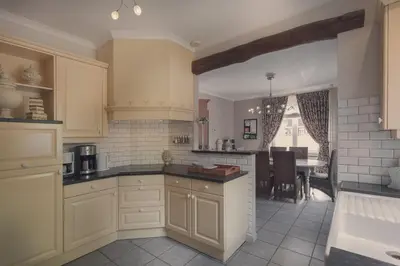a kitchen with white cabinets and a dining room at De Brugdraaier - The Bridge Turner in Neerpelt