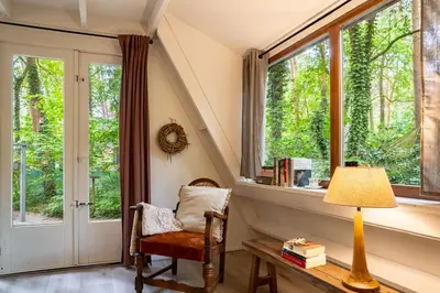 an attic room with a chair and a window at Boshuisje Rekem - Memories in Lanaken