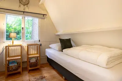 a bedroom with a white bed and a window at Boshuisje Rekem - Memories in Lanaken