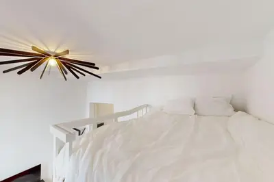 a bedroom with a white bed with a ceiling fan at House W 35 in Liège