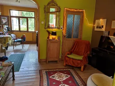 a living room with a chair and a mirror at Chez Marie in Liège
