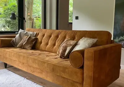 a brown couch with pillows on it in a living room at Eekhoorn-huisje, 4-pers bungalow, Rekem in Lanaken