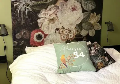 a pillow sitting on top of a bed with a flower wall at Eekhoorn-huisje, 4-pers bungalow, Rekem in Lanaken
