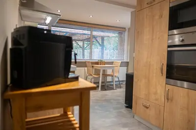 a kitchen with a television and a table with a dining room at Wellnesshuisje Pocono cabin in Lanaken
