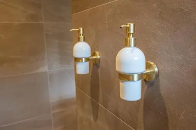 two white and gold wall lights in a bathroom at Wellnesshuisje Pocono cabin in Lanaken