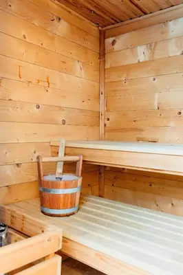 a wooden interior of a sauna with a bucket at 8P 4B Lanaken Retreat: Swimming Pool Jacuzzi and Sauna in Lanaken
