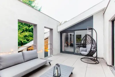 a patio with a couch and a chair at 8P 4B Lanaken Retreat: Swimming Pool Jacuzzi and Sauna in Lanaken