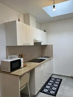 a kitchen with white cabinets and a microwave on a counter at Superbe studio à Liège in Saint-Léonard