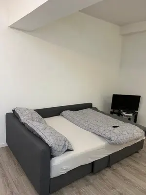 a bed in a bedroom with a white wall at Superbe studio à Liège in Saint-Léonard