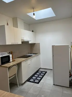a kitchen with white cabinets and a white refrigerator at Superbe studio à Liège in Saint-Léonard