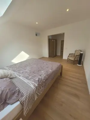 a bedroom with a bed and a chair at La grange aux anneaux in Beaurieux