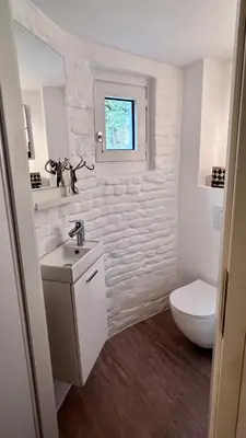 a white bathroom with a sink and a toilet at Petit Château in Eupen