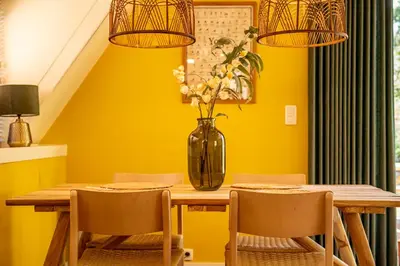 a dining room with a table and a vase with flowers at Boshuisje Rekem - Lotus in Lanaken