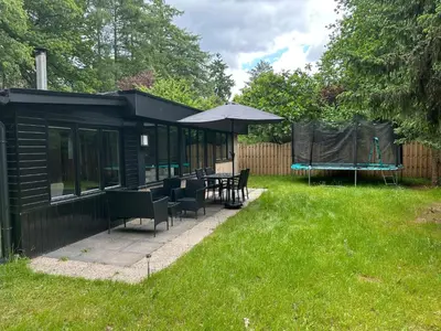 a black shed with a table and an umbrella at Etwee Vakantiehuis in Lanaken