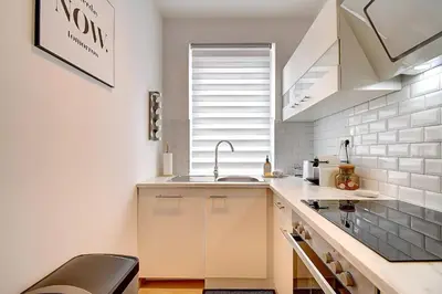 a kitchen with white cabinets and a sink and a window at - Le Cocoune - Cosy & Cute Flat in Liège