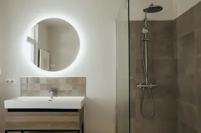 a bathroom with a sink and a shower with a mirror at La Terrasse des Guillemins by WelcHome in Liège