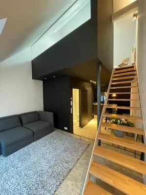 a living room with a couch and a staircase at Duplex in the historic heart of Liège - 3rd floor in Liège