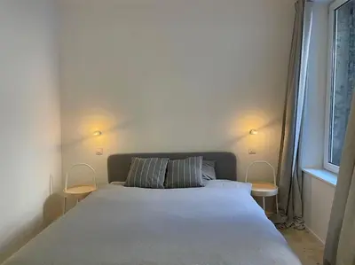 a bedroom with a bed with two chairs and a window at 2 bedroom duplex in the historic heart of Liège in Liège