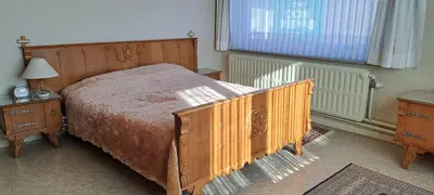 a bedroom with a wooden bed and a window at A home away from home in Oudsbergen