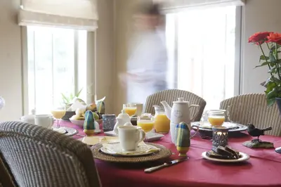 a table with a red table cloth with breakfast foods and orange juice at B&B Het Welthof in Bree