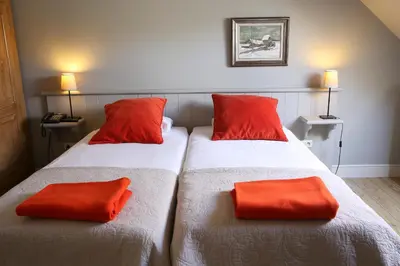 two beds with red pillows in a room at B&B Het Welthof in Bree