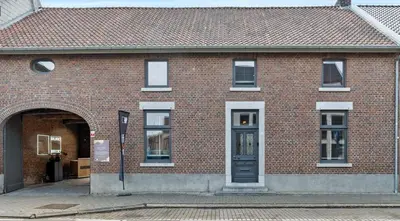 a brick building with a door and a street at Maison Quatre-Vingt-Deux in Maasmechelen