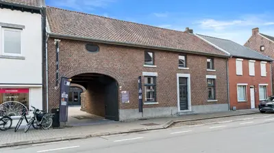 a brick building with an archway on a street at Maison Quatre-Vingt-Deux in Maasmechelen