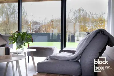 a living room with a couch with a blanket on it at Black Box by De Schrijfbar - vakantiewoning Haspengouw in Wellen