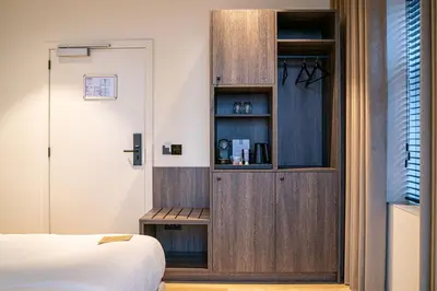 a bedroom with a wooden cabinet next to a bed at Boutique Hotel Annamaes, Maastricht-Hoge Kempen in Lanaken