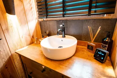 a bathroom with a white sink on a wooden counter at Het Zwart Schaap in Pelt