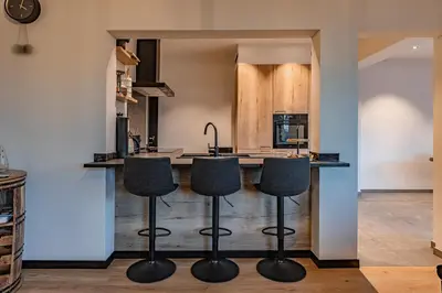 a kitchen with a bar with four stools at Villa Victoire in Heers