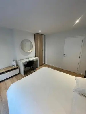 a bedroom with a large white bed and a desk at Magnifique appartement 1 chambre in Liège