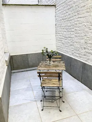 a table with a vase of flowers on a patio at Appartement 002 au rez-de-chaussée avant in Angleur