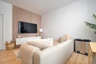 a living room with a white couch and a flat screen tv at - Suite Solvay - Cosy & Modern Flat in Liège