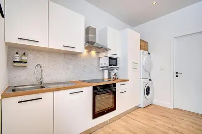a kitchen with white cabinets and a sink at - Suite Solvay - Cosy & Modern Flat in Liège