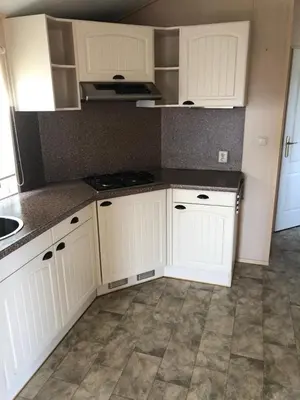 a kitchen with white cabinets and a tile floor at Chalet nr 17 Park Bergzicht Teuven in Voeren