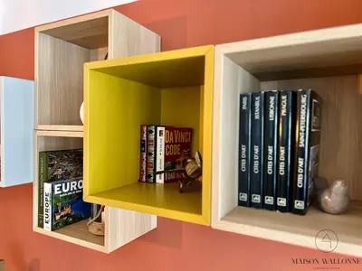 a yellow book shelf with books on it at L 'écrin sauvenière - Hypercentre avec Parking gratuit in Liège