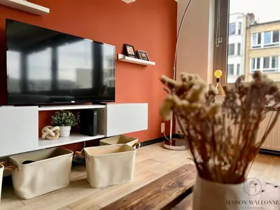 a living room with a television and a vase with flowers at L 'écrin sauvenière - Hypercentre avec Parking gratuit in Liège