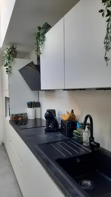 a kitchen with white cabinets and a black sink at Chambre d'hôte, la rouge in Liège