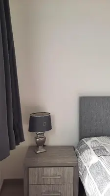 a lamp on a night stand next to a bed at Chambres d'hôte, la grise in Liège