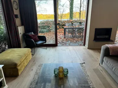a living room with a couch and a chair and a table at Forest lakehouse with Breathtaking Sauna in Lanaken