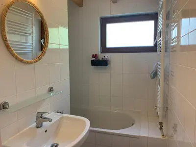 a bathroom with a sink and a tub and a mirror at Forest lakehouse with Breathtaking Sauna in Lanaken