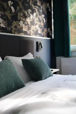 a bed with green and white sheets and a window at Min Su in Waremme