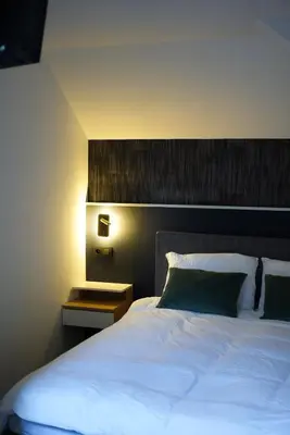 a bedroom with a white bed with a wooden headboard at Min Su in Waremme