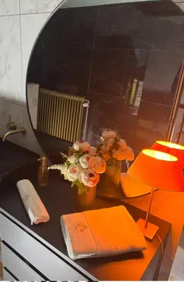a desk with a lamp and flowers and a mirror at Sophia Rooms 14 in Maasmechelen
