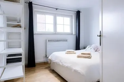 a bedroom with a white bed and a window at Villa Aluma in Sint-Truiden